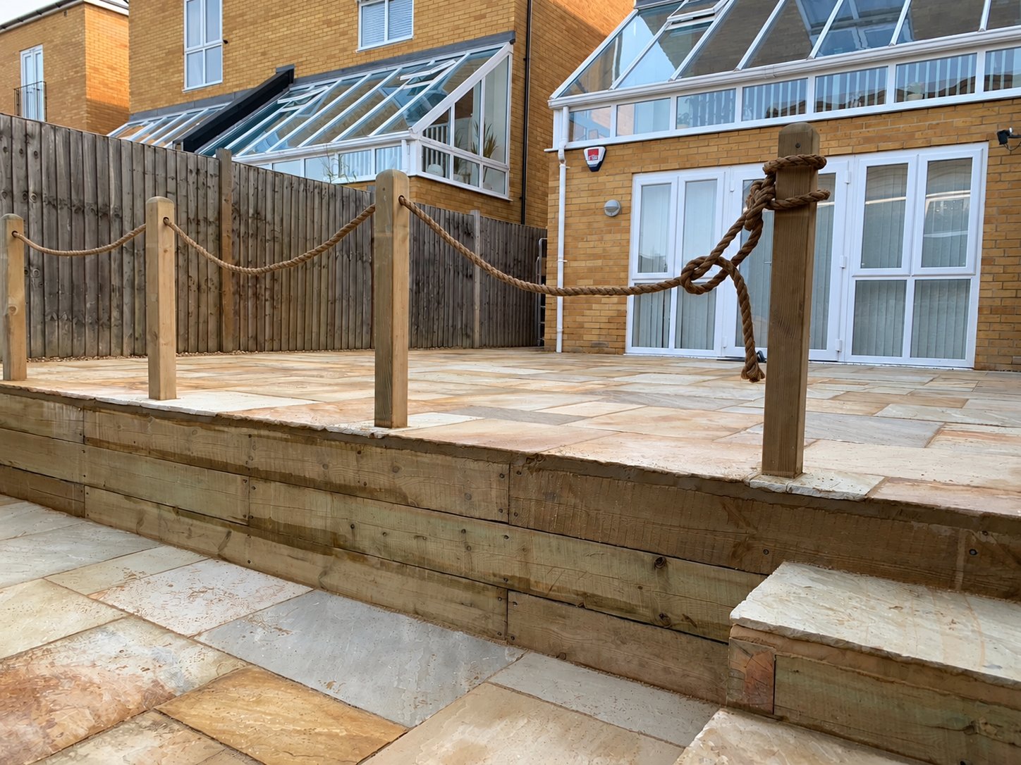 Sandstone paving and softwood sleeper wall in Ashford