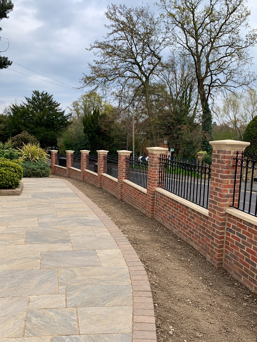 Brick piers with stone coping, pier caps and black railing panels in Chislehurst